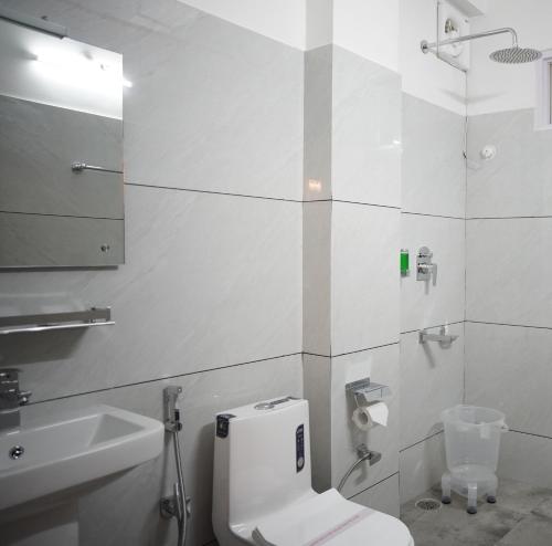 a white bathroom with a toilet and a sink at Hotel Arijika View in Kullu Manali