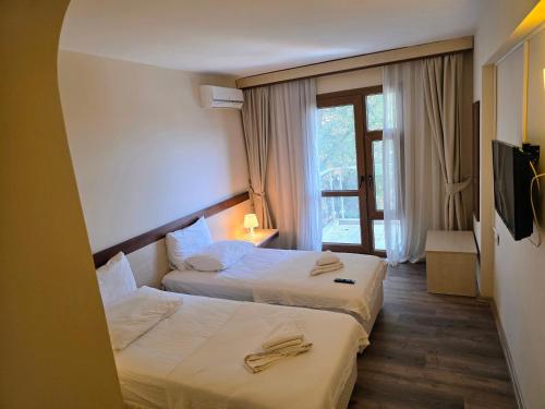 a hotel room with two beds and a window at Atlas Apart Hotel in Çeşme
