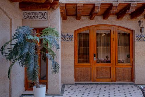 a palm tree in front of a house with a door at Asal Boutique Hotel in Bukhara