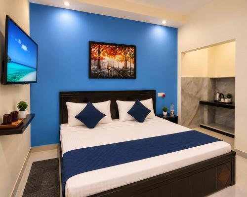 a bedroom with a blue wall and a bed at The Grand Blue Hotel in Greater Noida