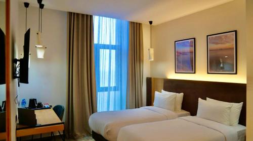 a hotel room with two beds and a window at Le Yot Hotel in 'Aïn Benian