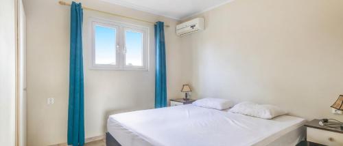 a bedroom with a white bed and a window at Wayaca Mini Resort in Willemstad