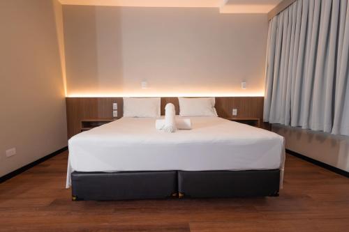 a bedroom with a large bed with white sheets at Hotel Évora by Rede Sagres in Florianópolis
