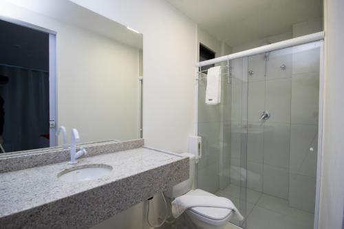 a bathroom with a toilet and a sink and a shower at Hotel Kazullo in Maceió