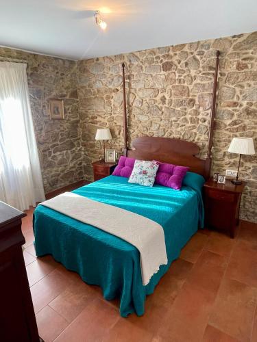 a bedroom with a large bed with purple pillows at Casa Rural A Redondiña in Lamas