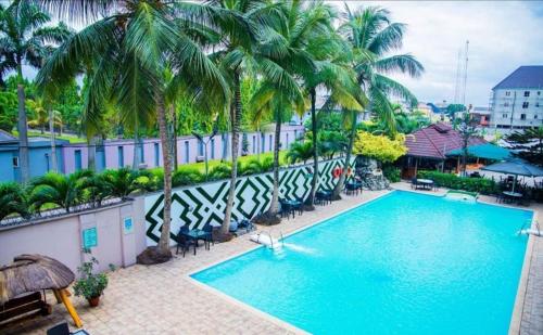 a swimming pool with palm trees and a building at Bougainvillea Hotels in Port Harcourt