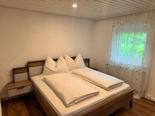 a bedroom with a bed with white sheets and a window at Ferienhaus Schmiedweg 10 in Altmünster