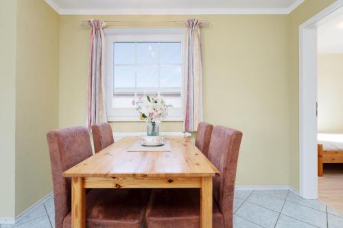 a dining room table with chairs and a vase of flowers at Dorfstraße 28 Seeadler in Klausdorf