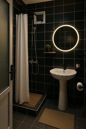 a black tiled bathroom with a sink and a shower at Heaven Boutique in Pucioasa