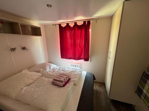 a bedroom with a bed with a red curtain at Mobilheim in Laichingen