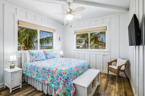 a white bedroom with a bed and a fan at CJ286FLR LUX-Parrotfish Point in Cudjoe Key