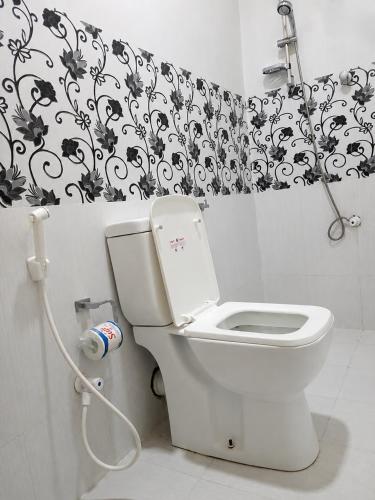 a bathroom with a toilet and a black and white shower curtain at Ceylon Beach haven Uppuveli in Trincomalee