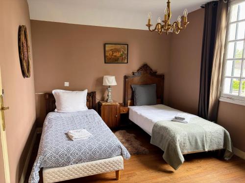 a bedroom with two beds and a chandelier at Maison de famille - Proche Centre Ville et Plage in Cabourg