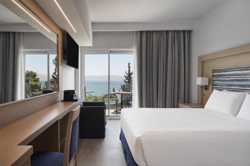 a hotel room with a bed and a view of the ocean at Paradise Resort Evia, a member of Radisson Individuals in Eretria