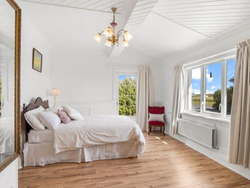 a white bedroom with a bed and a window at Conamara House in Ballyconneely