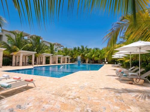 a pool at a resort with chairs and umbrellas at Playa Palmera Beach Resort in Punta Cana