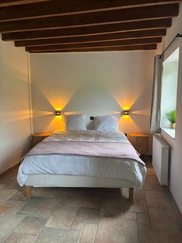 a bedroom with a bed with two lights on the wall at Maison Camille in Hotton