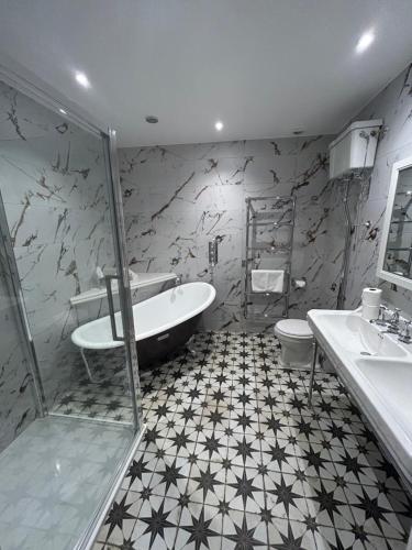 a bathroom with a tub and a toilet and a sink at The Mill Sharnbrook - Bedford in Sharnbrook