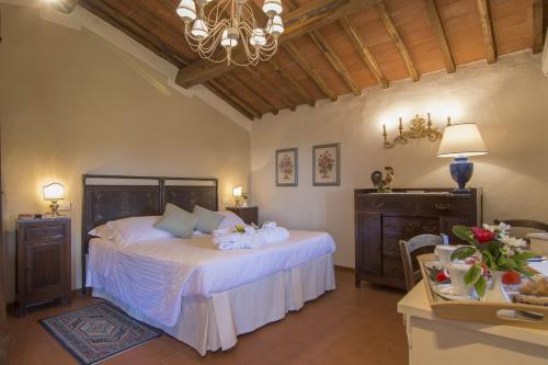 a bedroom with a bed with white sheets and a chandelier at Hotel Belvedere Di San Leonino in Castellina in Chianti