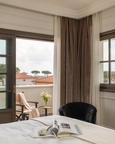a room with a bed with a book and a window at Villa Costanza Boutique Hotel in Forte dei Marmi