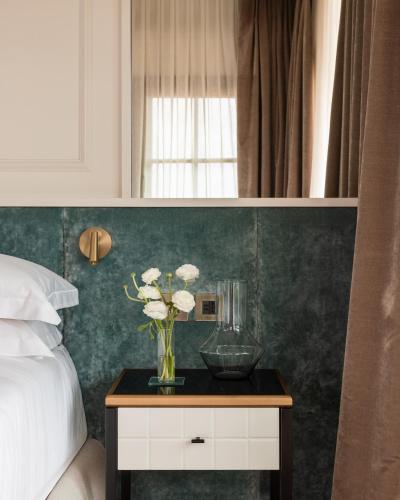 a vase of flowers on a table next to a bed at Villa Costanza Boutique Hotel in Forte dei Marmi