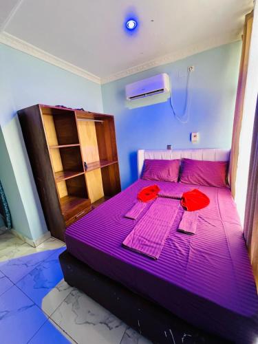 a purple bed in a room with red towels on it at RÉSIDENCE IDM-Ngoma in Kinshasa
