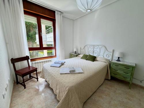 a bedroom with a bed and a chair and a window at Apartamento Playa Azul - 5924 in Arnuero