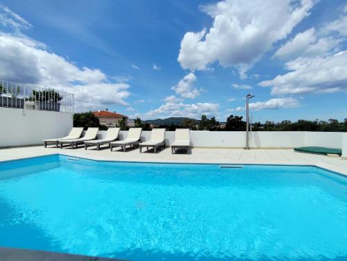a swimming pool with lounge chairs on a building at Villetta Borgo Bianco 1 con piscina in condivisione in Budoni
