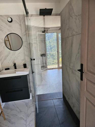 a bathroom with a shower and a sink and a mirror at Résidence E CIME ASCO Locations de studios meublés in Asco