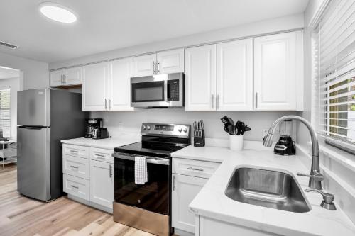 a kitchen with white cabinets and a stainless steel refrigerator at A Place in Paradise Unit B in Anna Maria