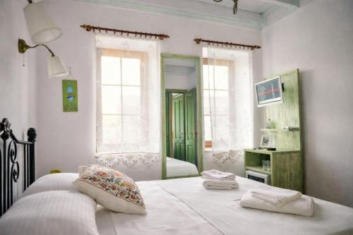 a bedroom with a bed with white sheets and windows at Just Datça in Datca