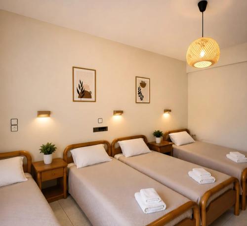 a room with three beds and a pendant light at Argyroupolis Dimitris Rooms in Argyroupolis