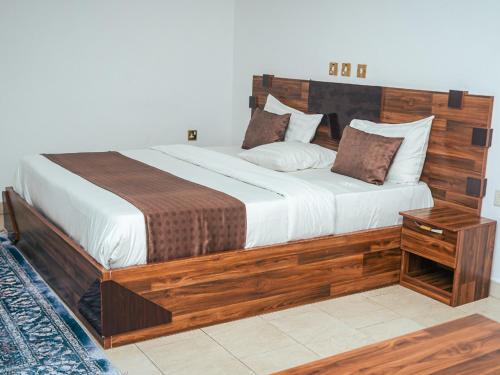 a large bed with a wooden headboard in a bedroom at Bougainvillea Hotels in Port Harcourt