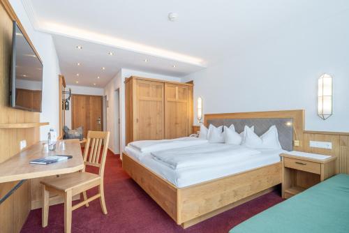 ein Schlafzimmer mit einem großen Bett und einem Schreibtisch in der Unterkunft Hotel Serles in Mieders