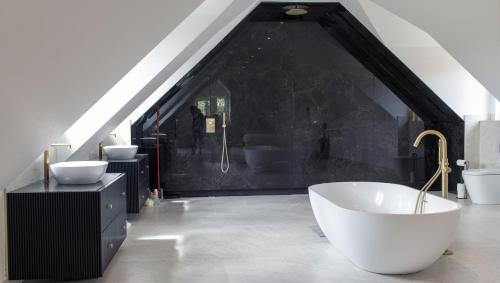 a bathroom with a white tub and a black wall at The Clock House in Sacomb