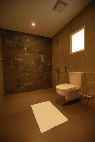 a bathroom with a toilet and a shower with a window at Fathima Residency in Pattanapuram