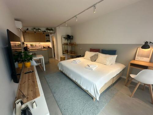 a bedroom with a white bed and a kitchen at Casa Alegria in Oeiras