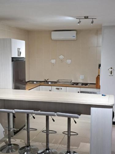 a kitchen with a table and some stools in it at Edaneg in Bloemfontein