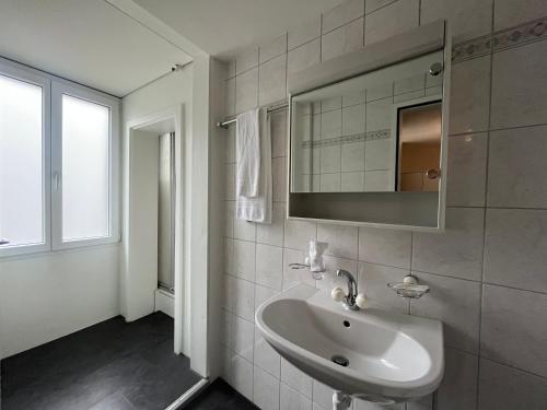 a white bathroom with a sink and a mirror at Hotel Sternen Budget in Lenk