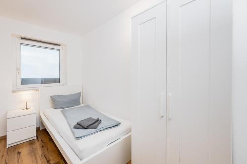 a white bedroom with a bed and a window at Schreinerfeld-Appartements in Ergolding