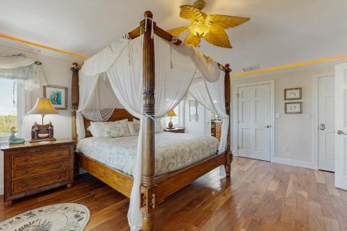 a bedroom with a canopy bed and a wooden floor at CJ314FLR The Mermaid Manor in Cudjoe Key