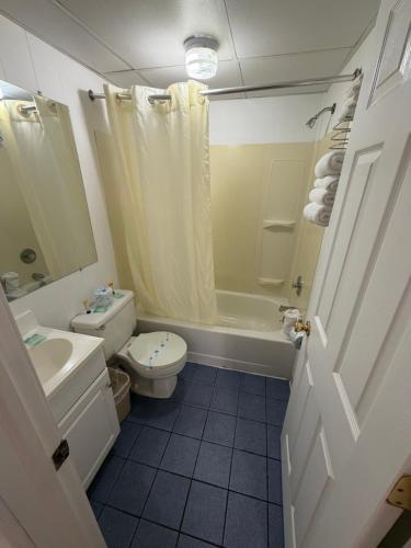 a bathroom with a toilet and a tub and a sink at Sunrise Motel in Seaside Heights