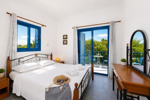 a bedroom with a bed and a desk and windows at Villa Rotiana in Polis Chrysochous