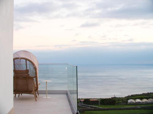 a chair on a balcony with a view of the ocean at Casa Conchita in Angra do Heroísmo