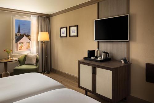 ein Hotelzimmer mit Bett und Fernseher in der Unterkunft NH Brugge in Brügge