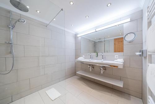ein Badezimmer mit Dusche, Waschbecken und Spiegel in der Unterkunft Hotel Serles in Mieders