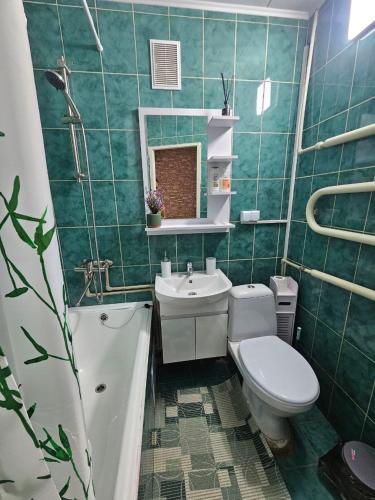 a green tiled bathroom with a toilet and a sink at Апартаменти Aura Bliss in Zhytomyr