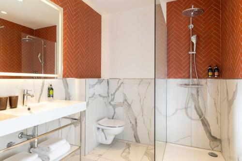 a bathroom with a shower and a toilet and a sink at Hotel The Augustin in Brussels