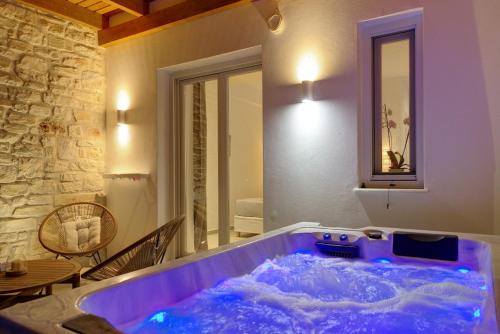a hot tub in a room with a stone wall at Sunshine Medousa Suite in Glifades