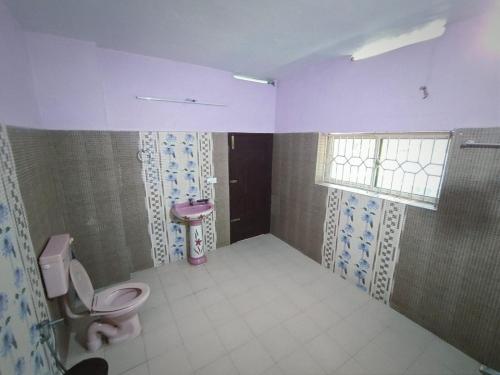 a bathroom with a toilet and a sink and a window at Harbour villa 1 in Trivandrum